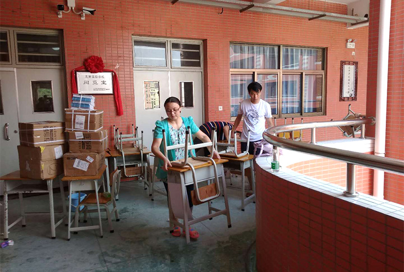 8868体育官网首页入口志愿者及家长用消毒液擦拭桌椅